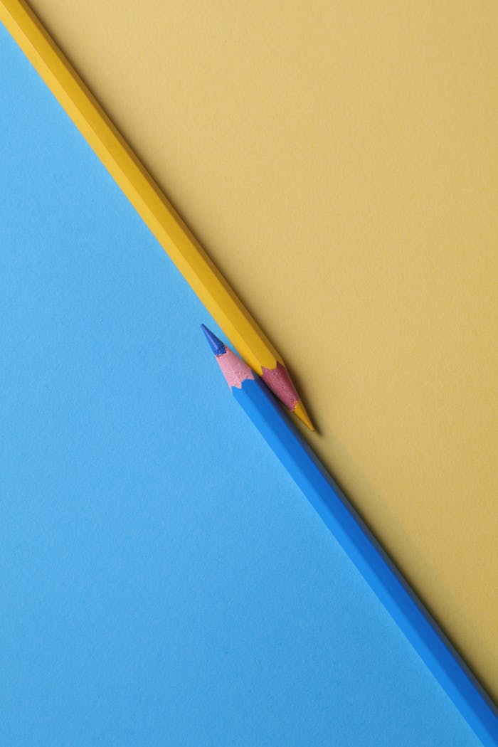 services-02 Close-up of vibrant yellow and blue colored pencils on contrasting paper backgrounds.